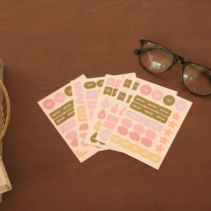 Set of planner stickers on a wooden surface with glasses in the background